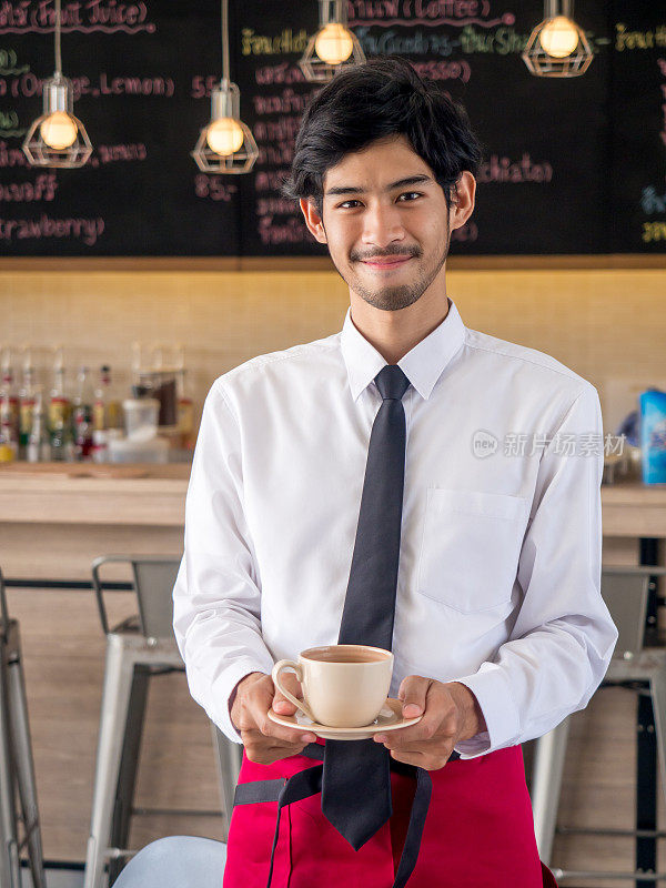 年轻的阿拉伯商人/老板/咖啡师面带微笑站在餐饮餐厅/咖啡馆/商店前